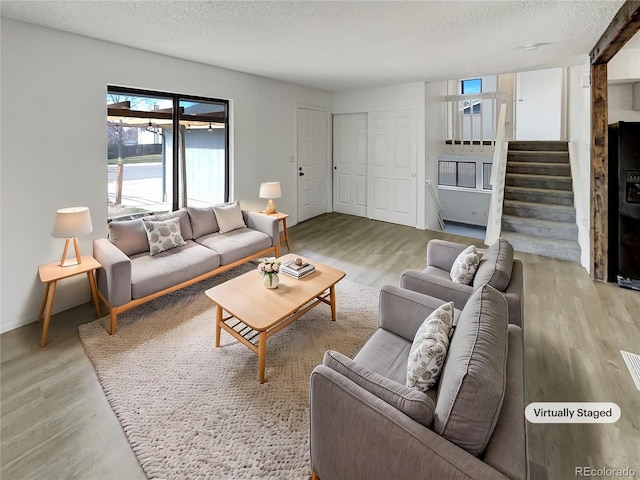 living area with stairway, a textured ceiling, and wood finished floors