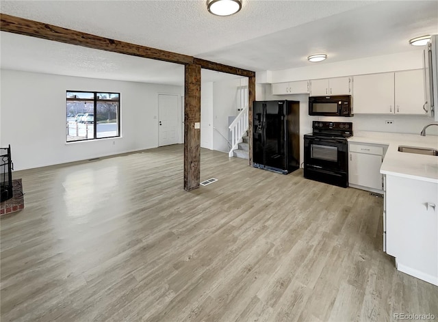 kitchen with black appliances, light wood-type flooring, light countertops, a textured ceiling, and a sink