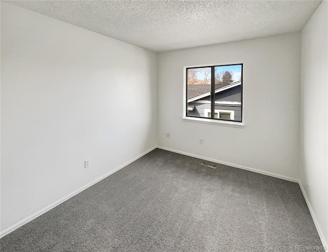 empty room with dark colored carpet, visible vents, baseboards, and a textured ceiling