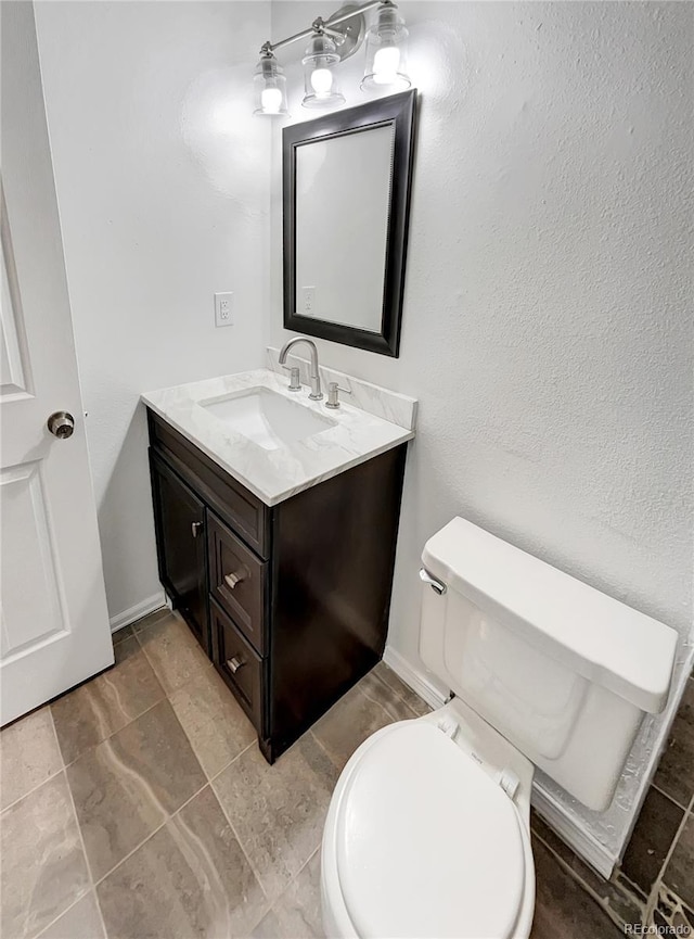 half bathroom with toilet, vanity, and baseboards