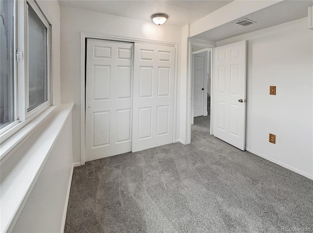 unfurnished bedroom featuring baseboards, visible vents, carpet floors, and a closet