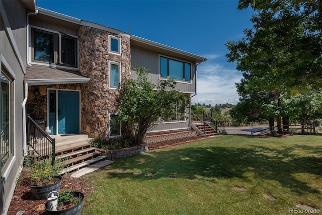 exterior space with stone siding and a lawn