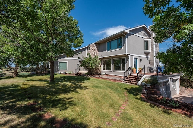 back of property featuring a yard, a deck, a garage, and stairs
