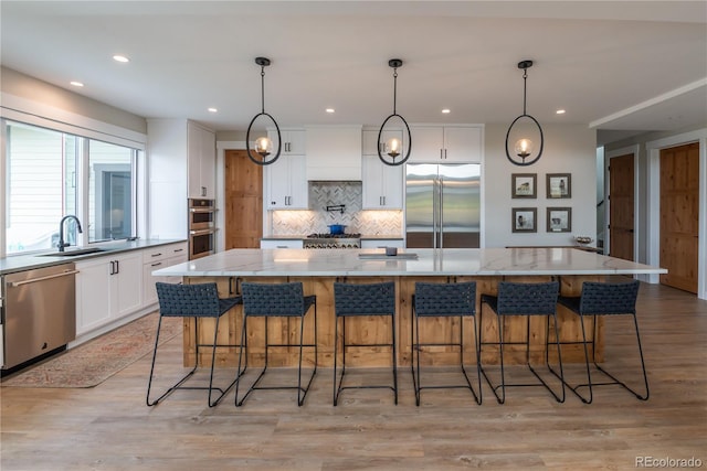 277 Hay Meadow Dr, Fraser, CO 80442 - kitchen with appliances with stainless steel finishes, a sink, backsplash, white cabinetry, and a breakfast bar