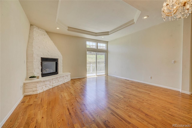2061 Cheyenne Summer Vw, Colorado Springs, CO 80904 - unfurnished living room featuring a tray ceiling, a fireplace, a chandelier, wood finished floors, and baseboards