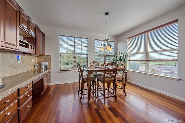 dining space featuring built in desk, dark hardwood / wood-style flooring, and a chandelier