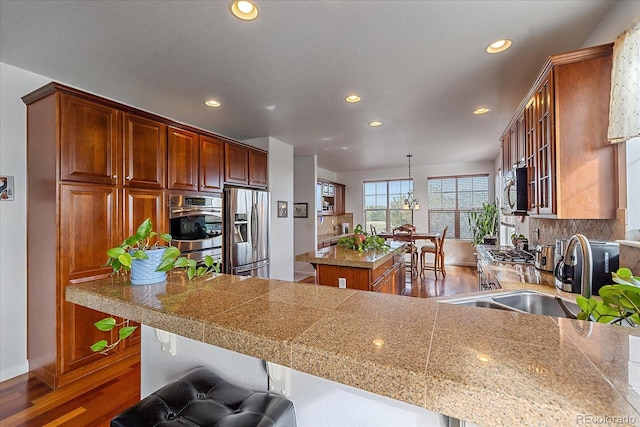 kitchen featuring hanging light fixtures, a kitchen island, decorative backsplash, stainless steel appliances, and dark hardwood / wood-style flooring