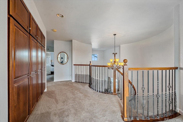 corridor featuring an inviting chandelier and light carpet