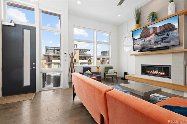 living room with dark hardwood / wood-style floors and a tiled fireplace