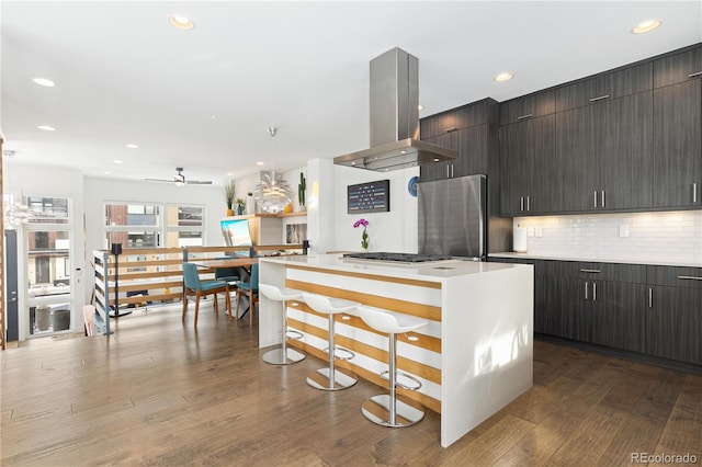 kitchen featuring wood-type flooring, pendant lighting, appliances with stainless steel finishes, island exhaust hood, and a kitchen island