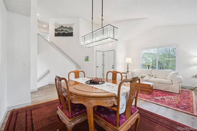 dining space featuring stairway, wood finished floors, lofted ceiling, recessed lighting, and a chandelier