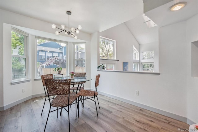 dining area featuring wood finished floors, a chandelier, baseboards, and vaulted ceiling