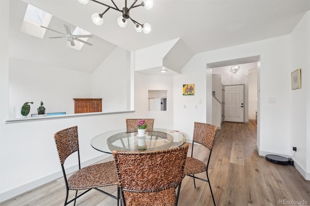 dining room with vaulted ceiling, wood finished floors, baseboards, a skylight, and a ceiling fan
