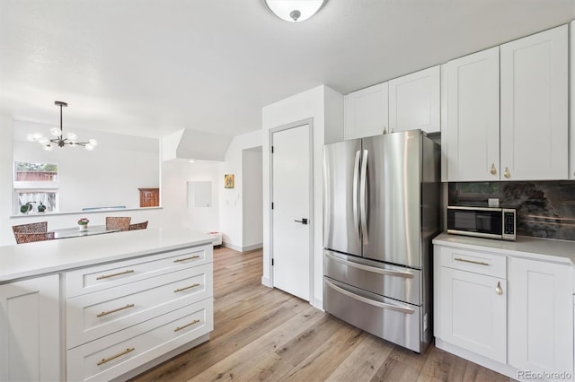 kitchen with stainless steel appliances, white cabinetry, a chandelier, and light countertops