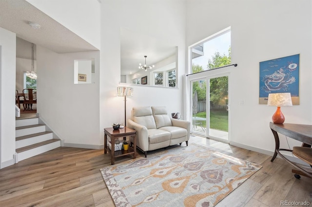 sitting room featuring a chandelier, a high ceiling, wood finished floors, baseboards, and stairs