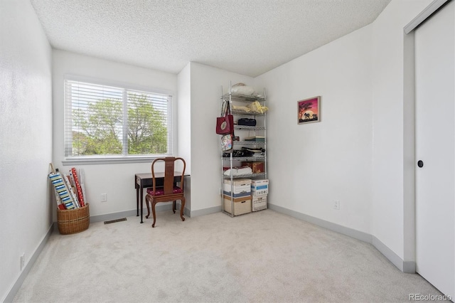 living area with carpet floors, a textured ceiling, and baseboards