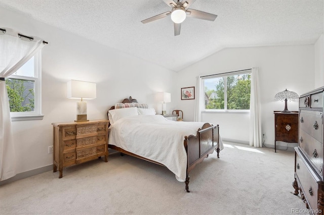 bedroom with light colored carpet, a textured ceiling, vaulted ceiling, baseboards, and a ceiling fan