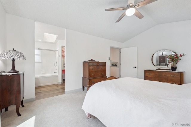 bedroom featuring lofted ceiling, light colored carpet, a skylight, baseboards, and ensuite bath