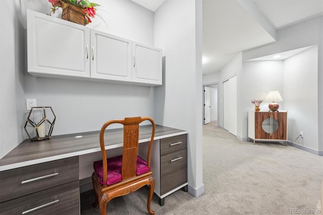 office featuring built in desk, light carpet, and baseboards