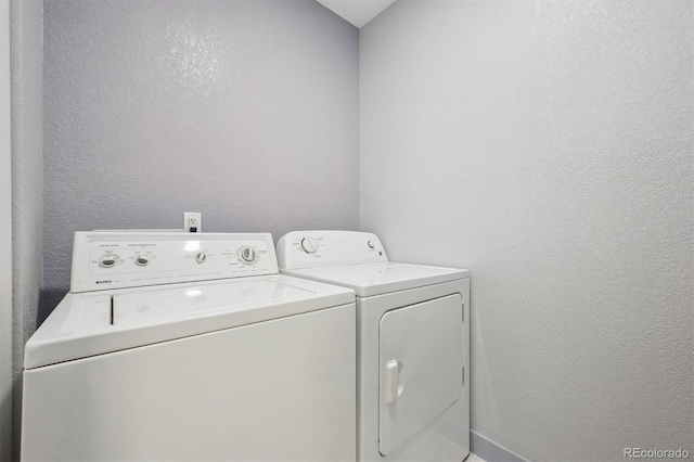 laundry room featuring washing machine and clothes dryer and a textured wall