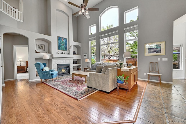 10653 W Parkhill Dr, Littleton, CO 80127 - living room featuring a towering ceiling, a ceiling fan, baseboards, healthy amount of natural light, and a tile fireplace