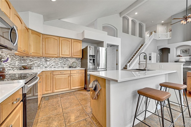 10653 W Parkhill Dr, Littleton, CO 80127 - kitchen with appliances with stainless steel finishes, a kitchen breakfast bar, tasteful backsplash, high vaulted ceiling, and a center island with sink