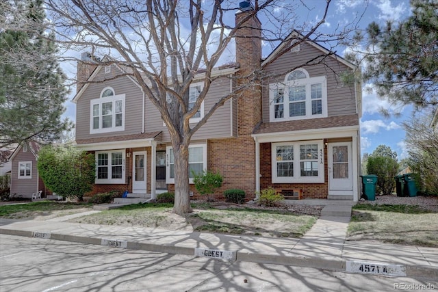 traditional-style home with brick siding, a chimney, and entry steps