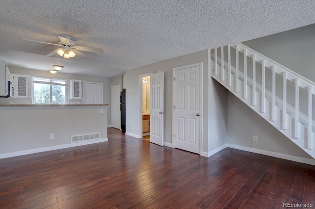 unfurnished living room featuring a textured ceiling, dark wood-style floors, baseboards, and a ceiling fan