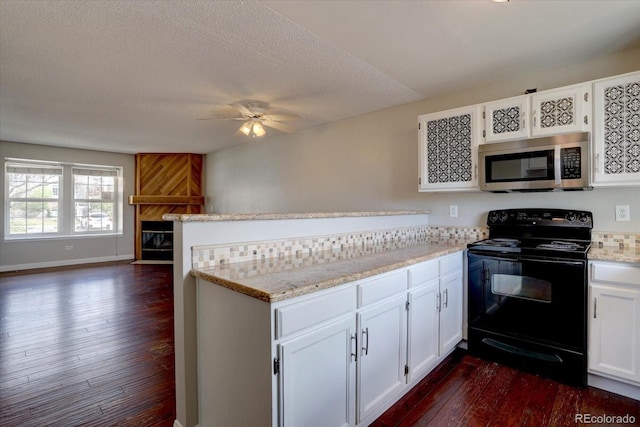 kitchen with stainless steel microwave, black electric range, a peninsula, dark wood finished floors, and open floor plan