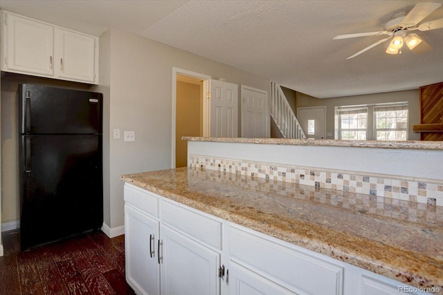 kitchen with freestanding refrigerator, a ceiling fan, white cabinetry, and light stone countertops