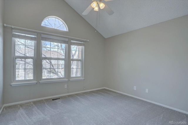 carpeted empty room with a ceiling fan, baseboards, and high vaulted ceiling