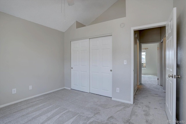 unfurnished bedroom with carpet flooring, vaulted ceiling, a closet, and baseboards