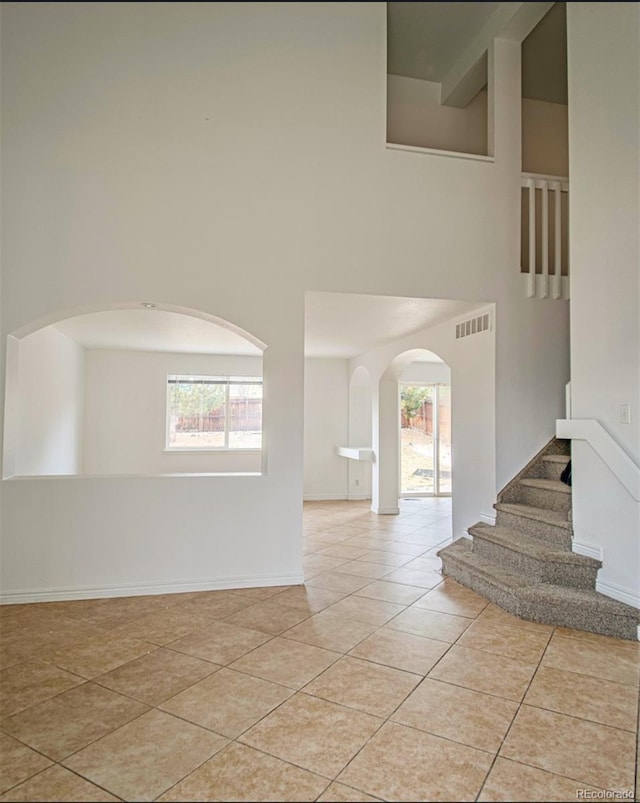 spare room featuring a towering ceiling and light tile patterned floors