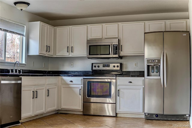 kitchen with stainless steel appliances, white cabinetry, and light tile patterned flooring