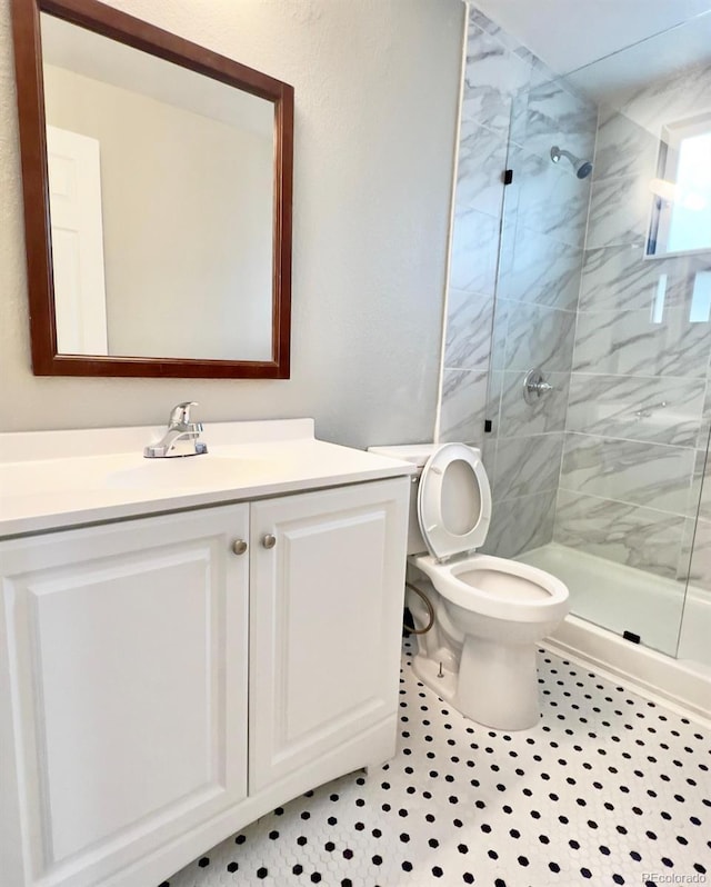 bathroom featuring tiled shower, vanity, tile patterned floors, and toilet