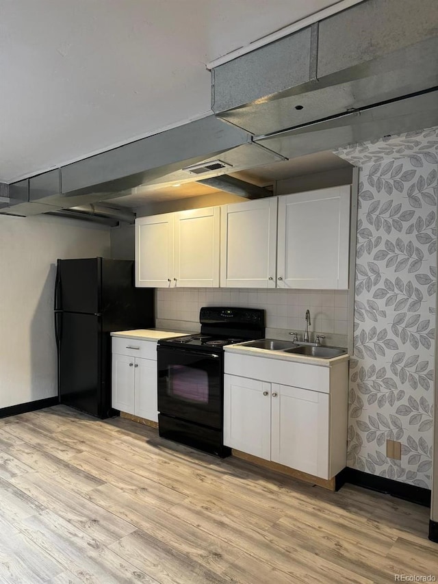 kitchen with backsplash, black appliances, white cabinets, sink, and light wood-type flooring