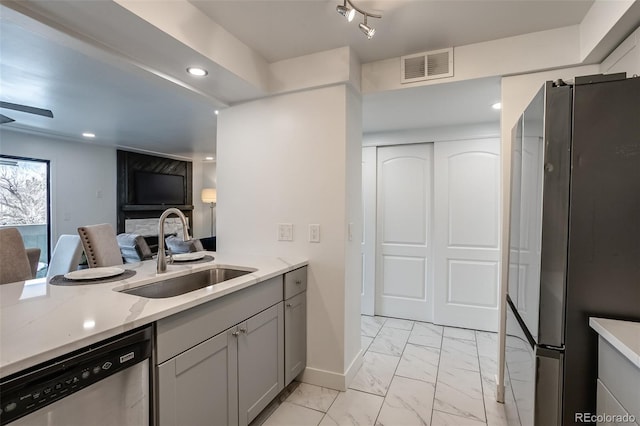 kitchen with gray cabinets, appliances with stainless steel finishes, sink, and light stone countertops