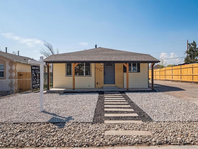 view of front of home with covered porch, fence, and roof with shingles