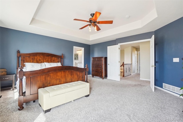 bedroom with carpet flooring, a ceiling fan, baseboards, a tray ceiling, and visible vents