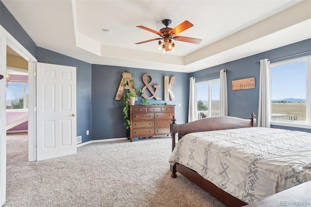 bedroom with a ceiling fan, baseboards, carpet, and a tray ceiling