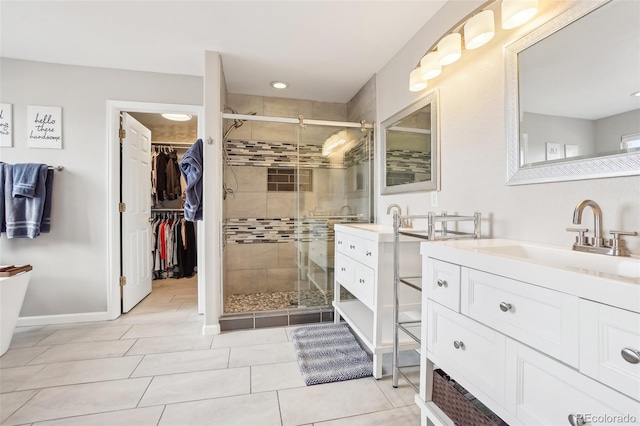 bathroom featuring tile patterned flooring, two vanities, a spacious closet, a sink, and a stall shower