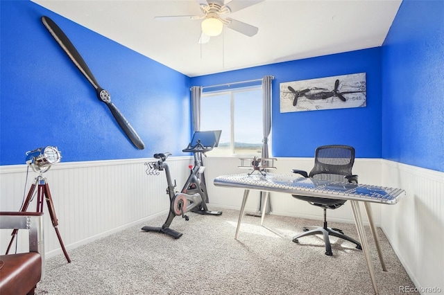 home office with carpet floors, a ceiling fan, and wainscoting