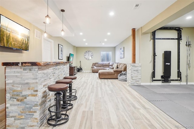 bar with decorative light fixtures, baseboards, a bar, and light wood-style flooring