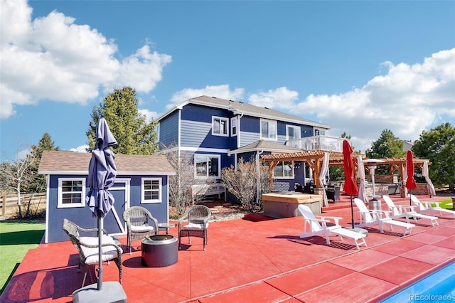 back of property with a pergola, a shingled roof, an outbuilding, and a patio