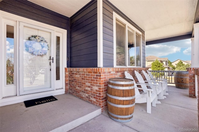property entrance with covered porch and brick siding