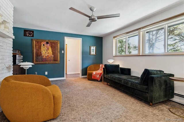 carpeted living area with a large fireplace, a ceiling fan, and baseboards
