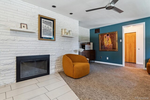 living area with ceiling fan, a large fireplace, baseboards, and tile patterned floors
