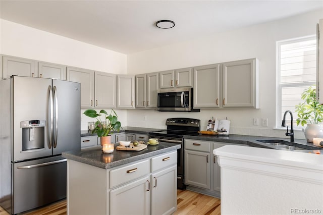 kitchen featuring sink, gray cabinets, stainless steel appliances, a center island, and light hardwood / wood-style floors