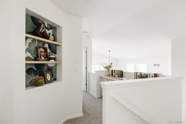 hallway featuring vaulted ceiling and light carpet