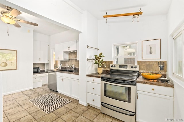 3147 W 39th Ave, Denver, CO 80211 - kitchen featuring appliances with stainless steel finishes, dark countertops, a sink, tasteful backsplash, and white cabinetry
